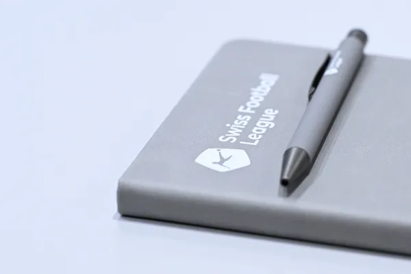 Symbolbild: Ein Foto eines Notizblocks mit dem Logo der Swiss Football League. Ein Kugelschreiber ist auf den Notizblock gelegt.